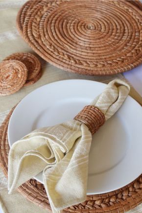 Minimal dining arrangement featuring a neutral linen napkin, handmade wicker napkin ring, white plate, and woven placemat
