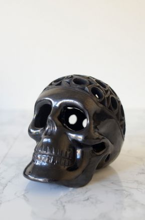 Close-up black ceramic skull with carved textures and reflective handmade finish
