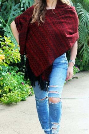Model wearing a red woven rebozo shawl with black tassel details.