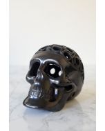 Close-up black ceramic skull with carved textures and reflective handmade finish