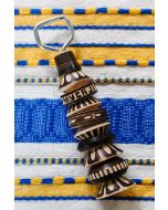 Decorative wooden bottle opener with black and natural wood carved patterns displayed on a blue and yellow woven textile.