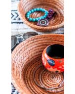Handwoven pine needle baskets organizing a painted bangle, beaded bracelet, watch, necklace, and sunglasses.